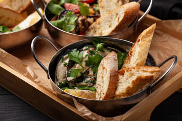 Freshly baked bread served with creamy dip and vegetables in a stylish serving tray