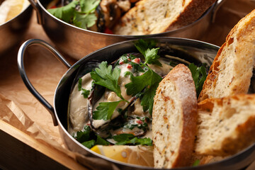Delicious seafood dish with mussels, herbs, and fresh bread served on a wooden tray in a cozy setting