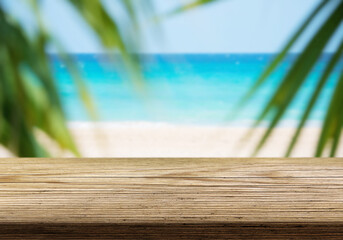 Beautiful tropical beach view with palm leaves framing a wooden railing on a sunny day