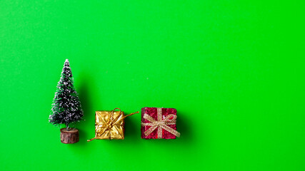 Holiday decorations featuring a small tree and colorful gift boxes on a bright green background