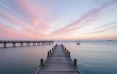 Fototapeta premium Solitary Wooden Dock at Dawn on a Misty Pink Lake 