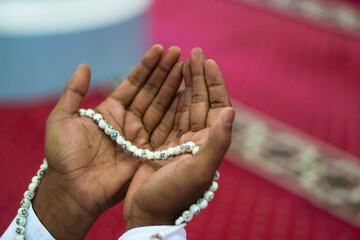 Closeup, A person who raises both hands with prayer beads while praying to God
