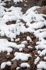 A detailed vertical shot of a ground covered in brown and grey rocks, with soft, white patches of...