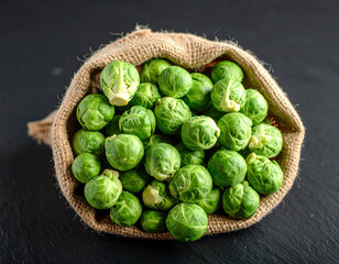 Fototapeta premium A sack of Brussels sprouts isolated on a dark background.