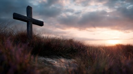 Solitary wooden cross stands on a hill at sunset