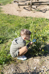 Curious child exploring nature with magnifying glass in park