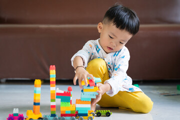 Naklejka premium Child Playing with Colorful Building Blocks Indoors