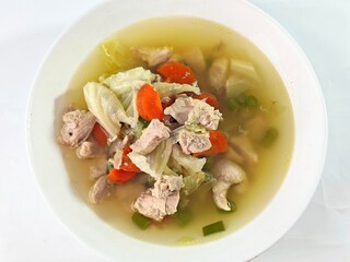 Hearty Chicken Soup with Cabbage and Carrots in White Bowl Top View.