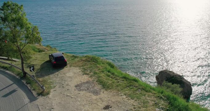 SUV parked on a grassy area overlooking a serene sea view