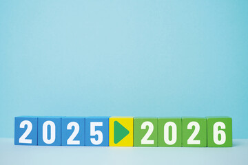Colorful wooden blocks displaying the transition from the year 2025 to 2026 with an arrow...