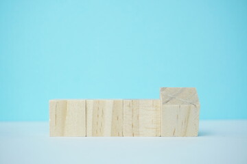 Wooden blocks arranged symmetrically on a blue background representing concepts of organization, creativity, and education alongside a blank space for input of symbols or text for diverse uses.