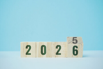 Wooden blocks representing the transition between 2025 and 2026 on a light blue background