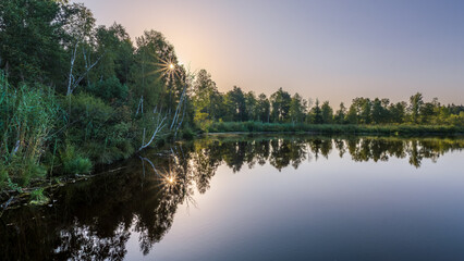 Sunrise over a calm lake with trees and reflections in the Pfrunger-Burgweiler Ried nature reserve, Germany