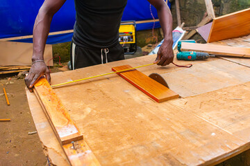 Young African carpenter standing, cutting wooden board