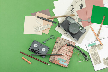 Flat lay with vintage camera, cassette, notebook, key and research tools on green background