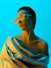 Close-up of model wearing silver draped fabric and white angular sunglasses, highlighted by bold...