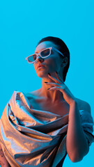 Futuristic female in silver draped fabric and white sunglasses. Concept of avant-garde fashion,...