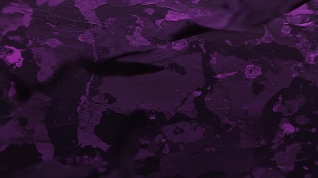 A close up of a purple textured surface with dark patches and subtle details seen