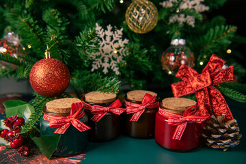Christmas aroma candles with fir cones on the table with the Christmas tree on a background