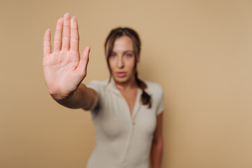 Woman signaling to stop with hand raised in front of a neutral background during a calm moment