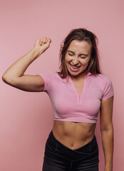 Joyful woman celebrating success in fitness attire against a pink background