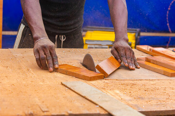 Young African carpenter standing, cutting wooden board