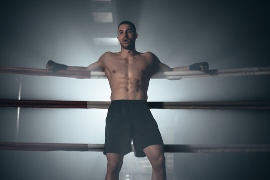 Fighter leaning on the ropes of a boxing ring. High quality photo