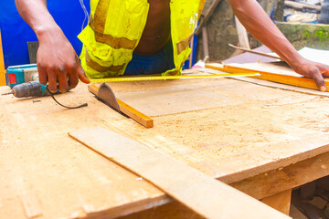 Young African carpenter standing, cutting wooden board