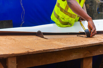 Young African carpenter standing, cutting wooden board