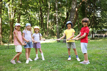 Obraz premium Cute little kids playing tug of war in park