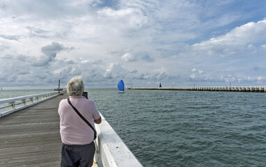 Fototapeta premium The river Yser flows into the North Sea at the town of Nieuwpoort entre deux jetée de bois, promenade des beaux jours ez des vacances