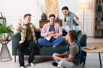 Friends laughing on sofa indoors. Positive emotion