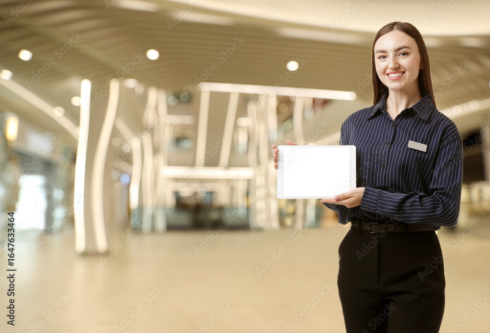 Poster young hostess with tablet computer in hotel lobby. space for text