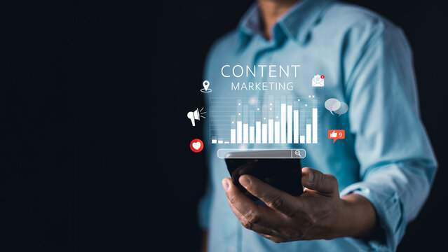 person in a blue shirt holds a smartphone displaying a glowing digital content marketing interface with graphs,likes,comments,and icons,representing social media strategy and online brand engagement.