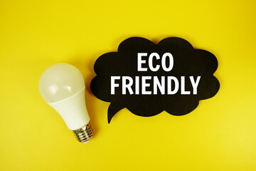 Eco Friendly text on speech bubble with light bulb top view on yellow background