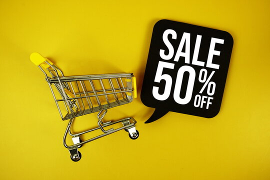 Sale 50% text on speech bubble with mini trolley shopping cart top view on yellow background