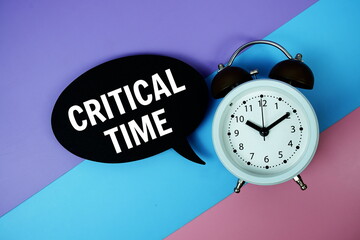 Critical Time text on speech bubble with alarm clock top view on blue, purple and pink geometric...