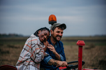 Smiling farmers driving a tractor in their field