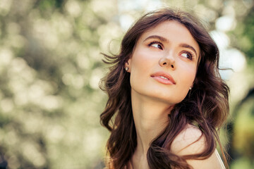 Beautiful young woman in a nature setting with bokeh effect background exuding charm and elegance