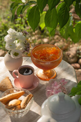 Berry jam in a glass bowl on a table in a sunny summer garden