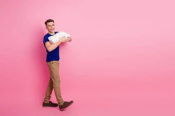 Joyful man with brown hair holding neat packages against pink background, showcasing casual style and cheerful attitude