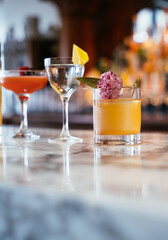 Elegant spring cocktail lineup on marble bar with floral garnish and citrus accents