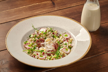 Okroshka decorated with pea sprouts being served with kefir on wooden table