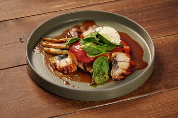 Grilled eel with vegetables and stracciatella cheese on wooden table