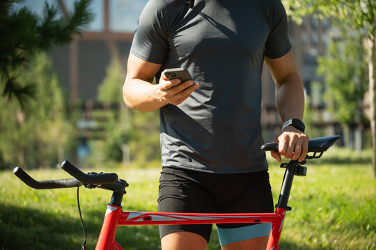 Cyclist with mobile phone check apps in public park. Summer. Outdoor activity. - Powered by Adobe