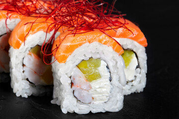 Philadelphia uramaki sushi rolls covered with salmon and red spice threads presenting shrimps and...