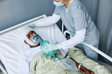 HIgh angle view of Caucasian nurse working in modern hospital doing artificial ventilation for...