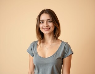 Obraz premium A smiling young woman with shoulder length brown hair and a gray shirt against a beige background