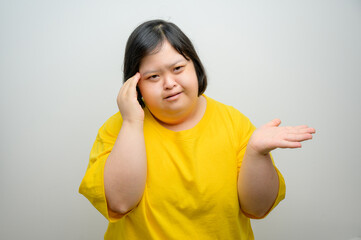 Portrait of an Asian woman with Down syndrome, touching her temple with one hand and raising the...