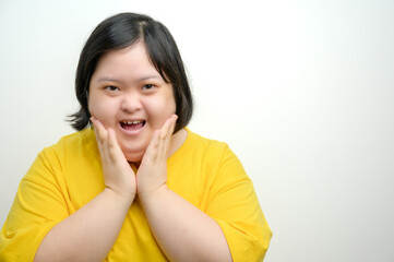 Portrait of an Asian woman with Down syndrome, smiling with both hands on cheeks in a surprised and...